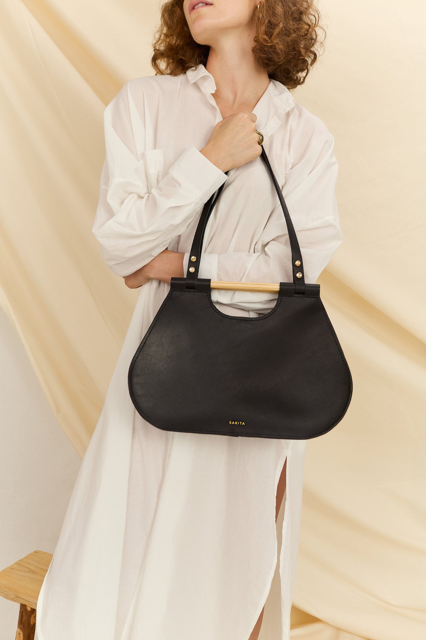 Model faced forward holding the Ophelia black leather tote bag in front of her