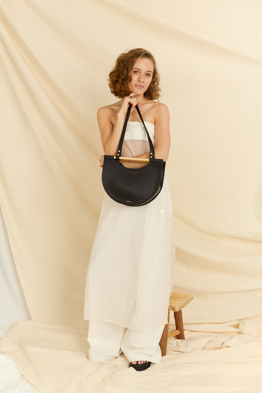 Front view a model holding the Celine half moon leather bag in black
