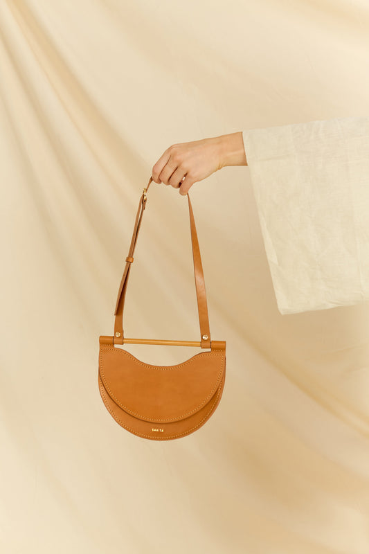 Front view of the Elodie leather shoulder bag hand held by a model