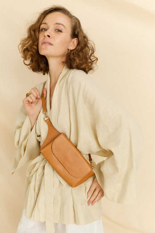 Model faced forward wearing the Effie leather belt bag in tan across her chest