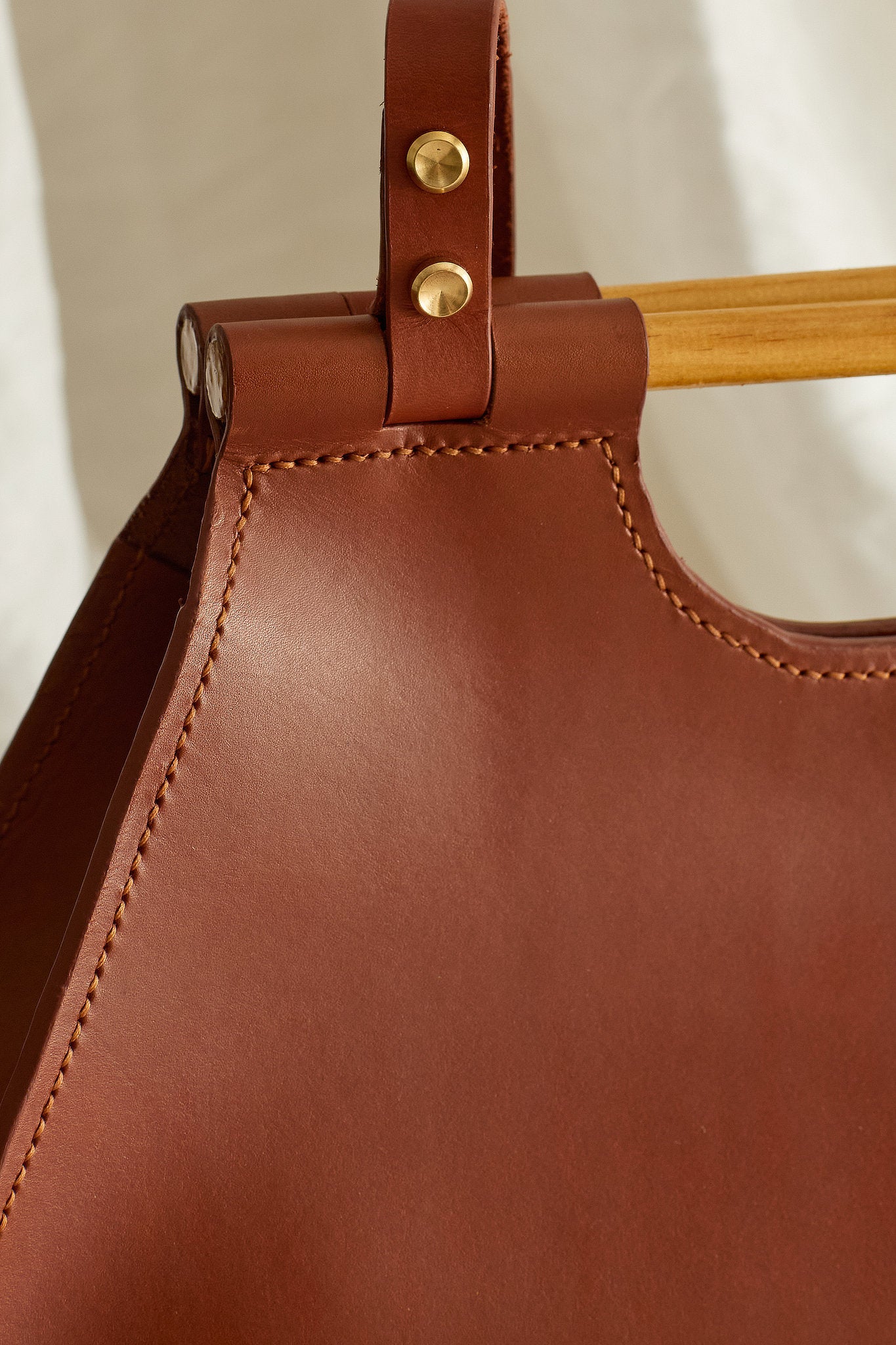 Close up on stitching and brass detail of the Ophelia leather tote bag in maroon