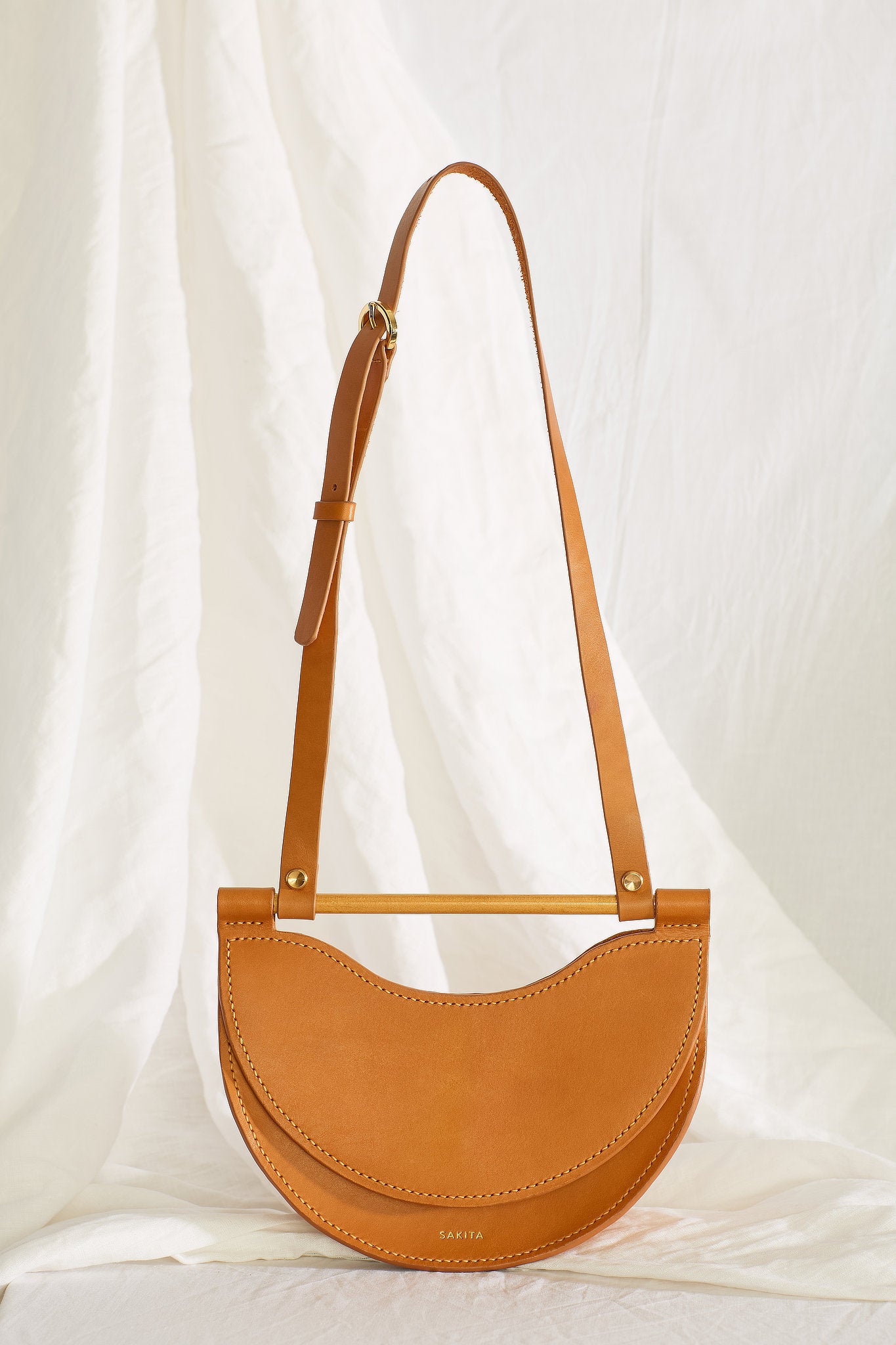 Front view of the Elodie mini half-moon leather shoulder bag in tan colour