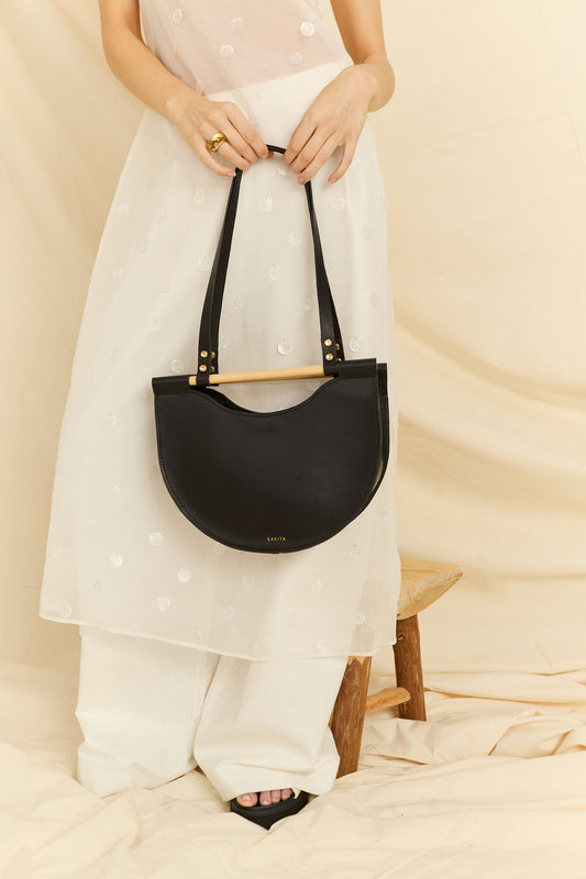 Close of up a model holding the Celine half moon leather bag in black