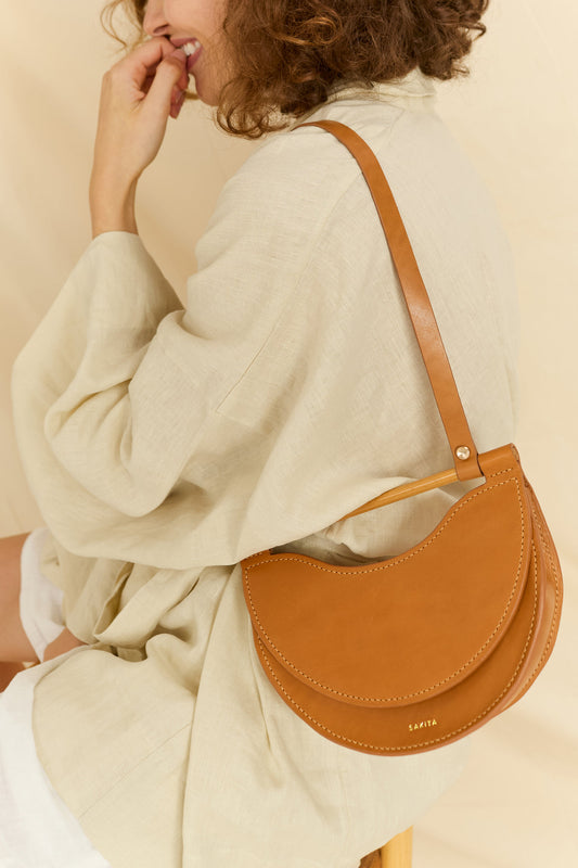 Model wearing the Elodie mini half-moon leather bag over the shoulder