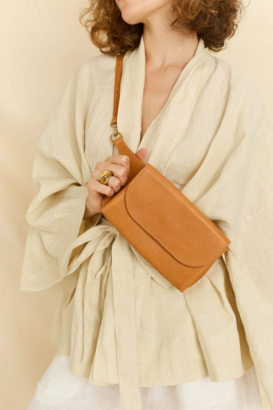Model faced forward wearing the Effie leather belt bag in tan across her chest