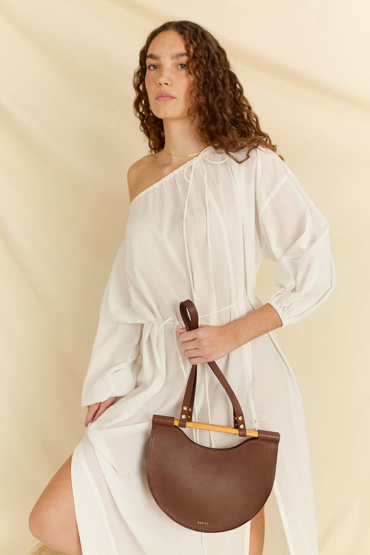 Model holding the Celine half moon leather bag in brown facing forward