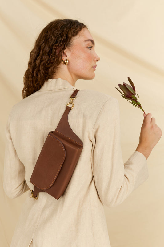 Model with her back turned wearing the Effie leather belt bag in brown across the back